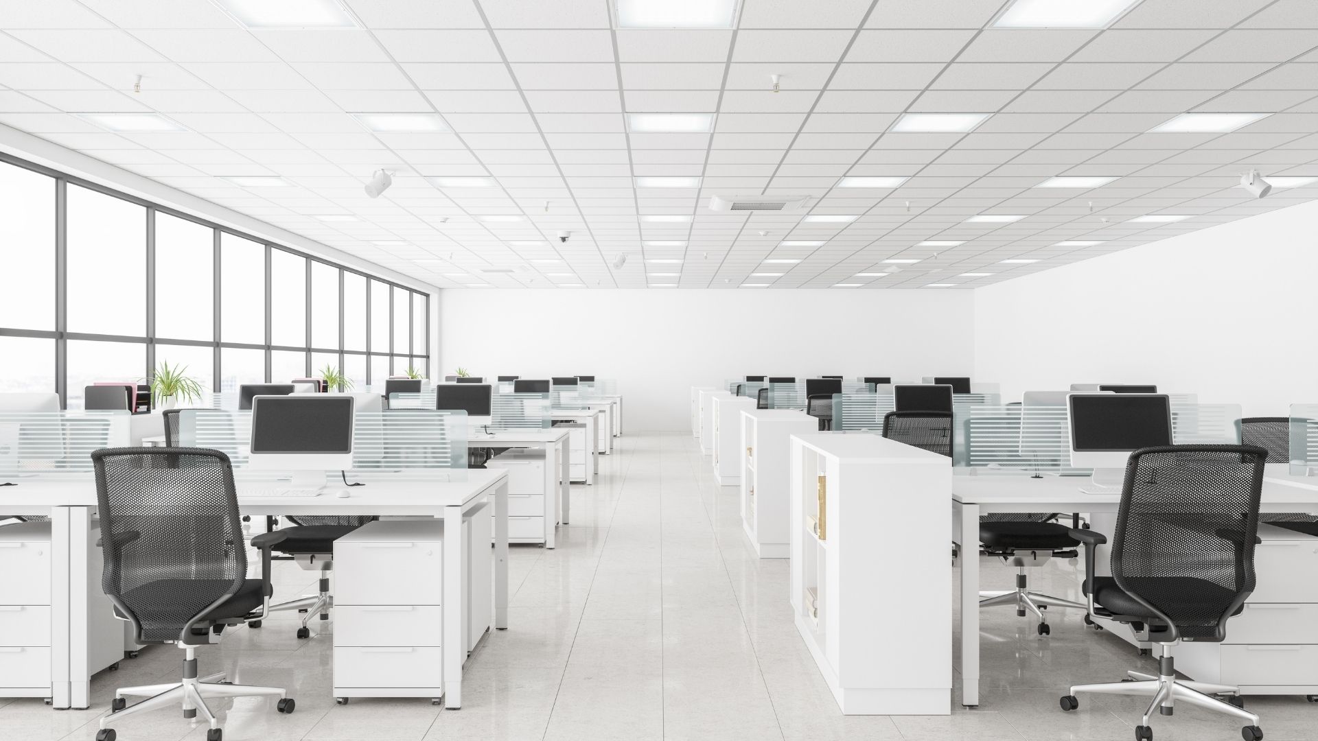 Jasne biuro typu open space z białymi biurkami i fotelami ergonomicznymi, w którym zachowana jest wysoka higiena pracy.