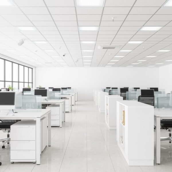 Jasne biuro typu open space z białymi biurkami i fotelami ergonomicznymi, w którym zachowana jest wysoka higiena pracy.